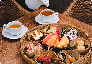 Tea being poured beside a bamboo platter of assorted Asian-inspired appetizers served at a wellness retreat