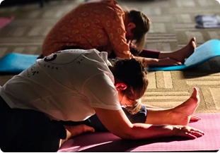 Yoga participants practicing a seated forward fold stretch on mats indoors at a retreat